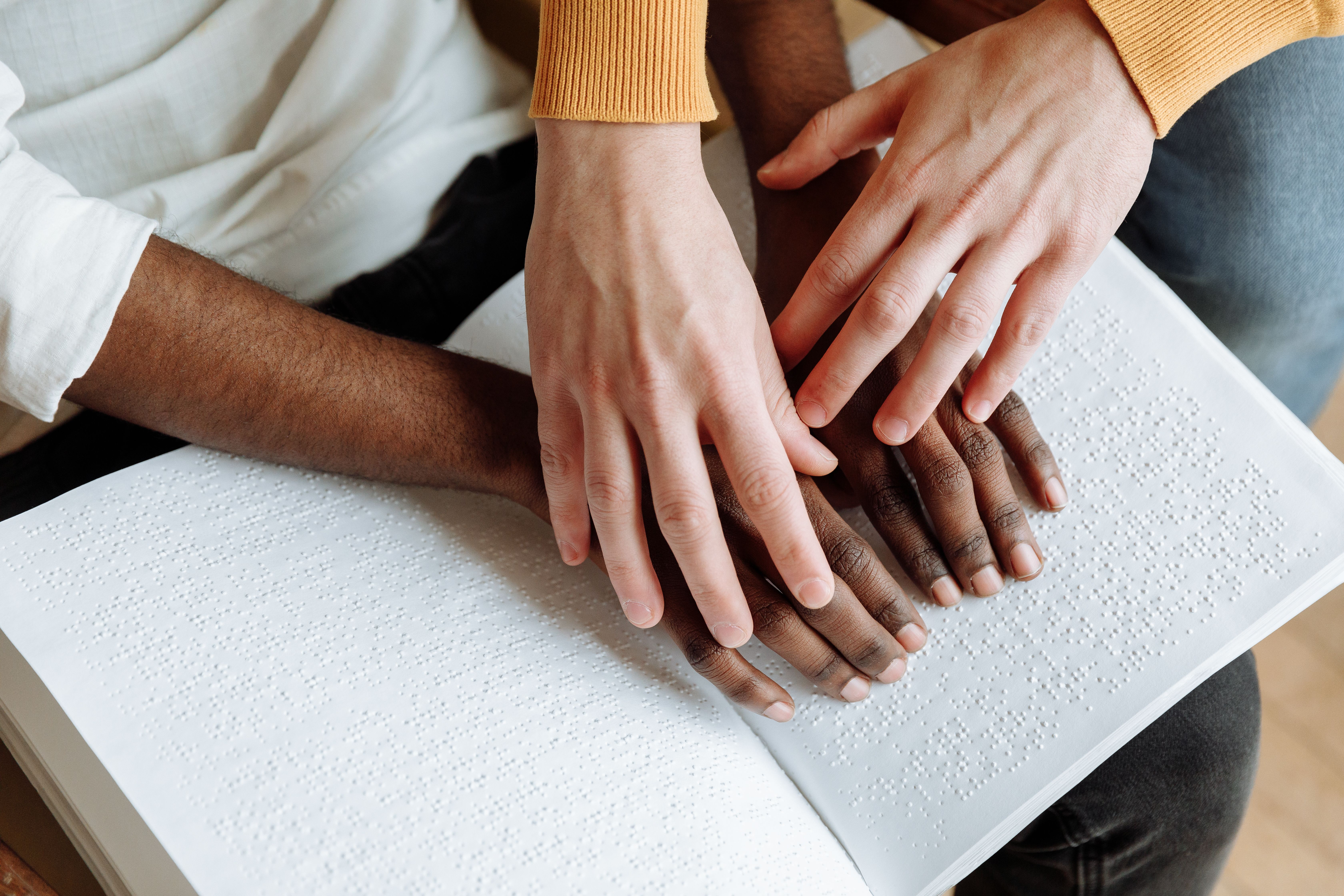 disabilità sensoriale, mani di non vedenti su libro